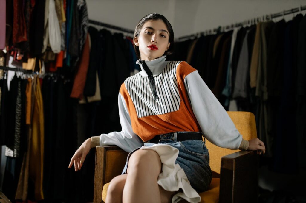 Confident woman in a stylish retro outfit posing on a chair. Vintage fashion in a modern setting.