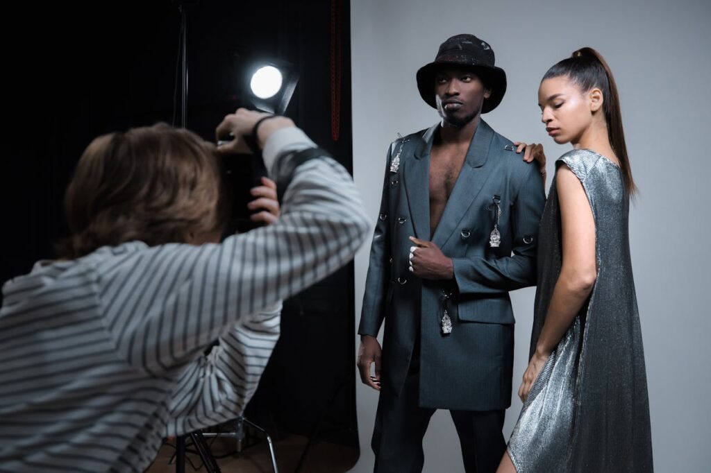 A male and female model posing for a fashion photoshoot in a studio setting.